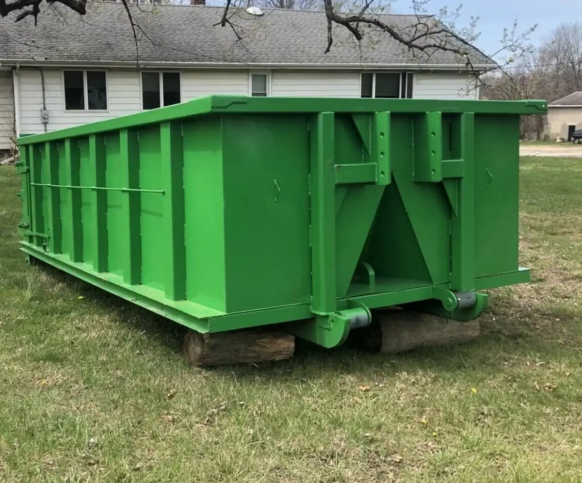 Roll-off dumpster resting on wood boards in a residential yard